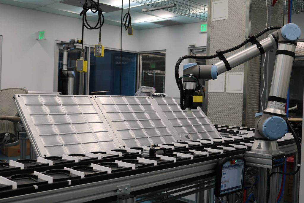 A robotic arm stands stationary next to a conveyor belt in a lab.