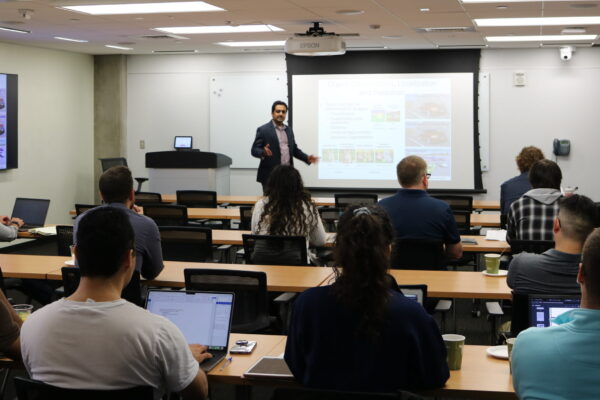 Professor giving lecture to class in front of projector