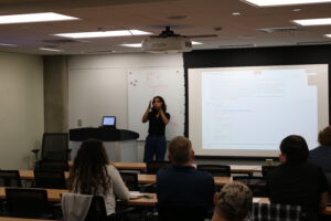 Individual giving lecture to class in front of projector screen