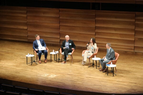 Three panelists and a moderator seated on a stage having a discussion