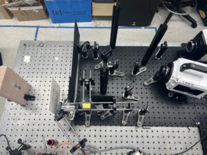 A collection of camera equipment and lenses is arranged on an optical table. This makes up SHEAR-IFS.