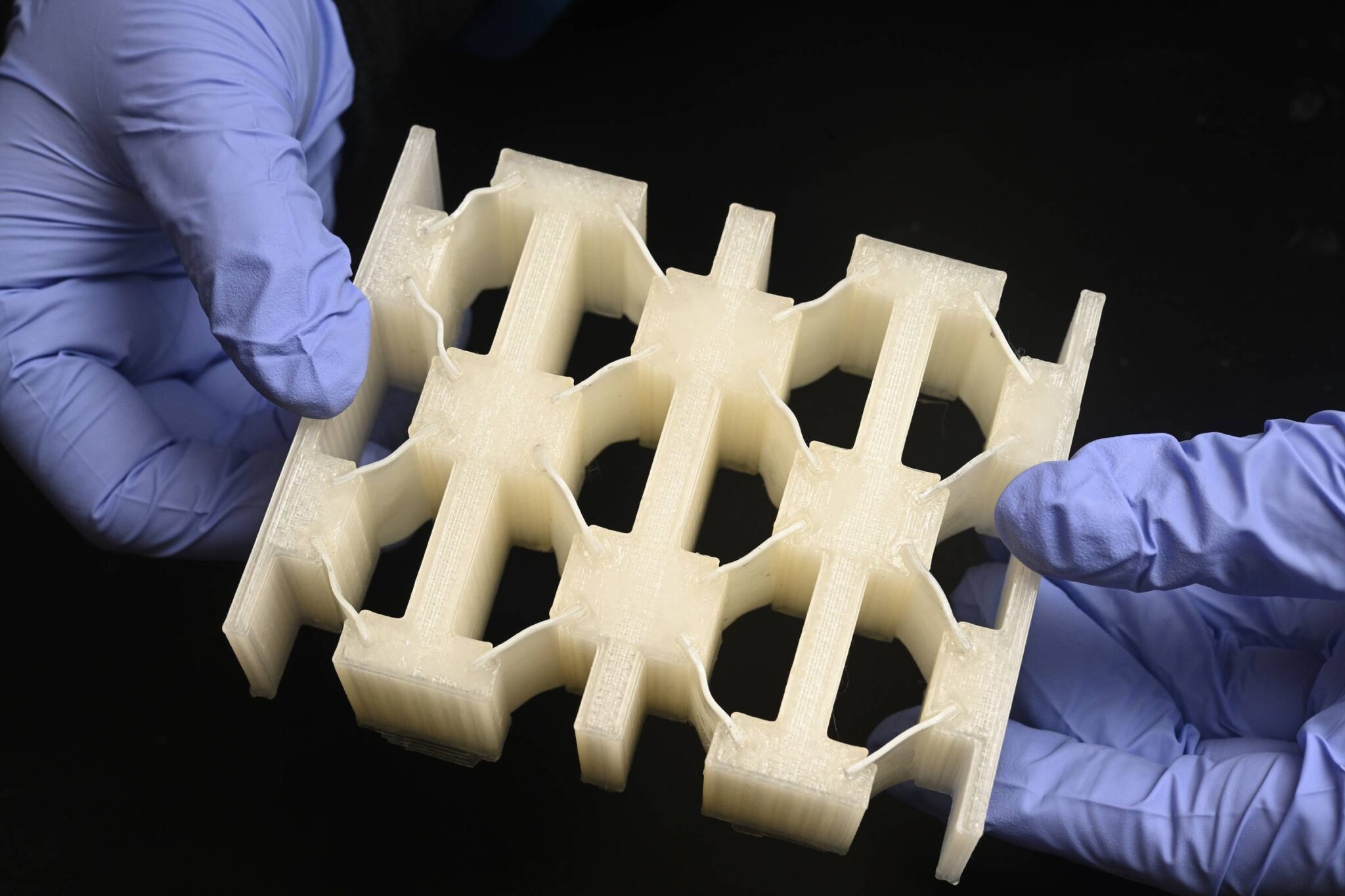 gloved hands hold a matrix-like material sample
