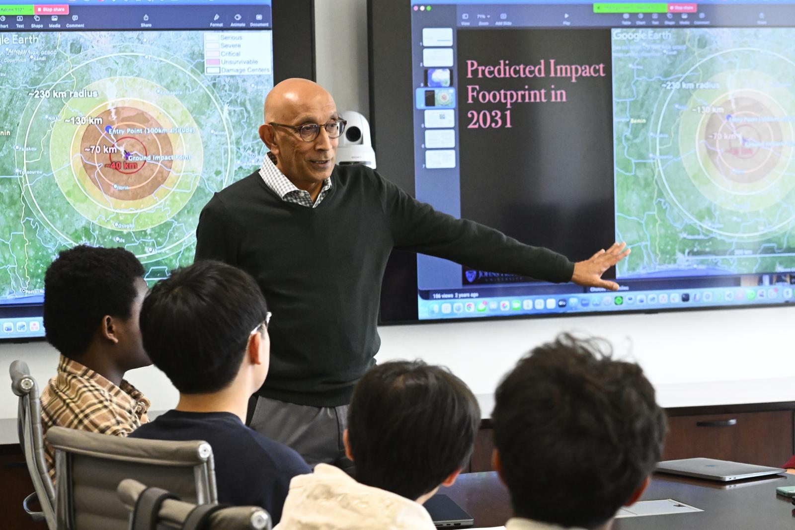 KT Ramesh addresses an undergraduate class. The slideshow in the background shows a predicted impact footprint for the class's simulated asteroid.